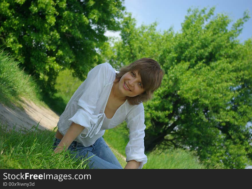 A young attractive woman sitting in a path on a warm summer day