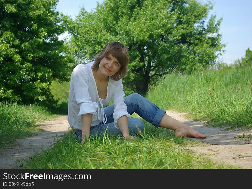 A young attractive woman sitting in a path on a warm summer day