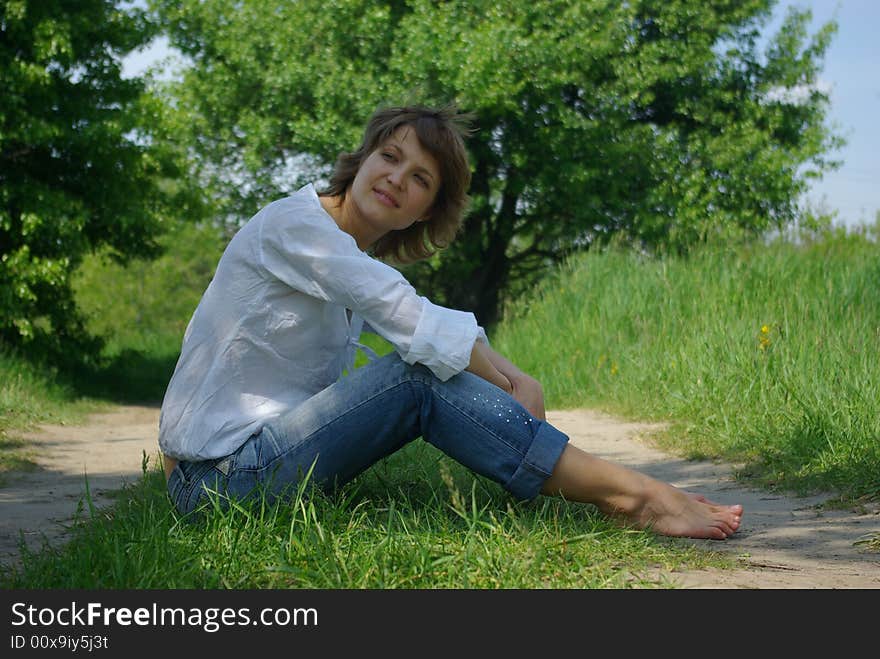 A young attractive woman sitting in a path on a warm summer day