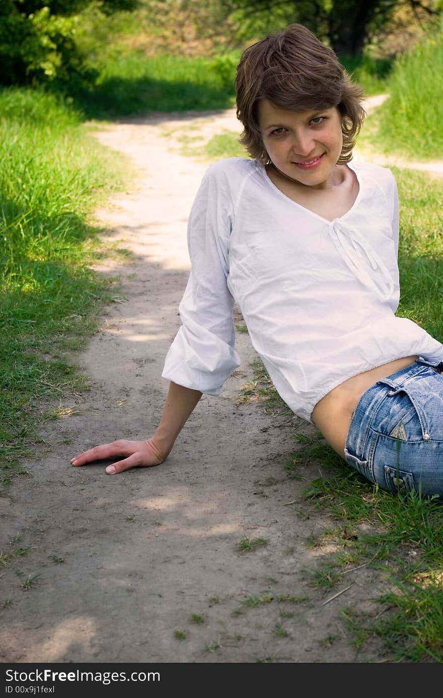 A young attractive woman sitting in a path on a warm summer day