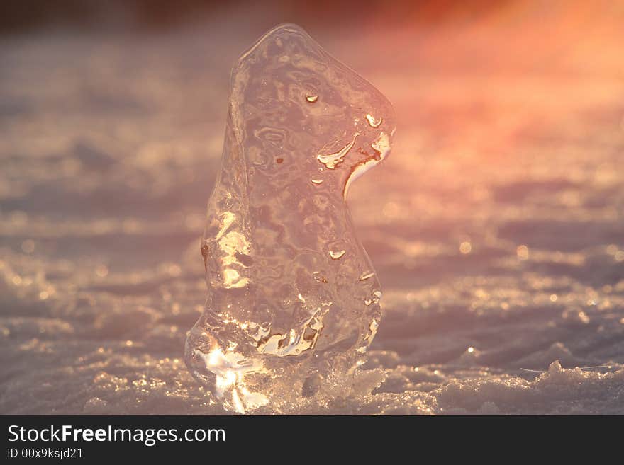 The piece of ice is in spring orange sunlight.