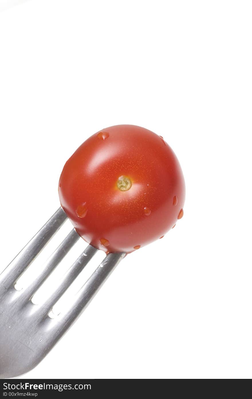 Fresh red juicy tomato with water droplets on a fork