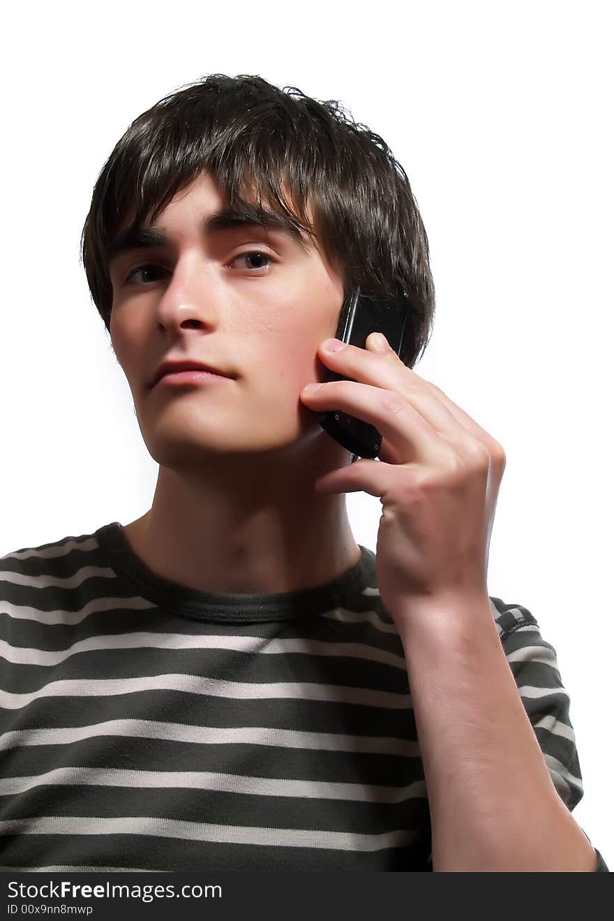 A portrait about a trendy handsome guy who is speaking with somebody by mobile phone and he has a glamorous look. He is wearing a striped t-shirt.