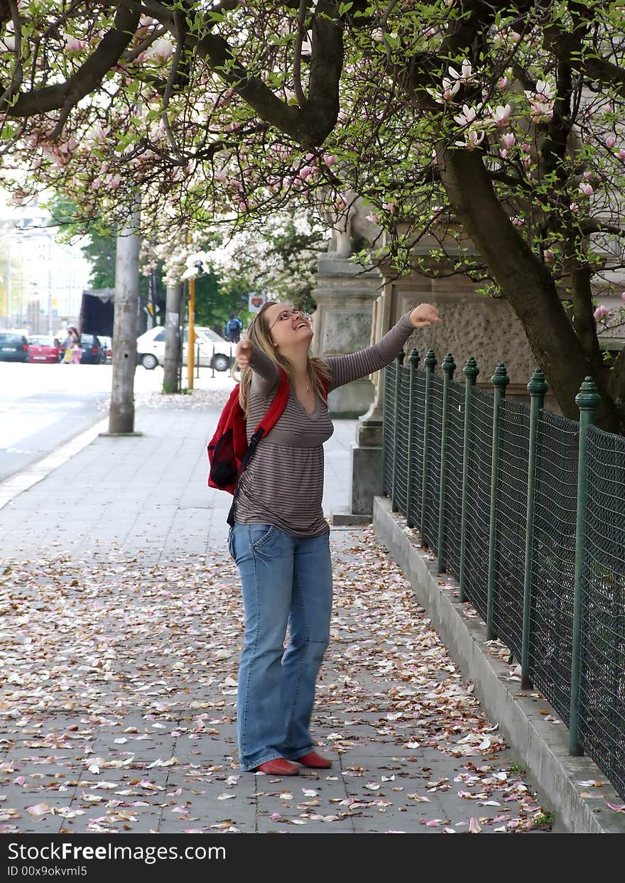 The young beautiful girl in the street rejoices to spring flowering of trees. The young beautiful girl in the street rejoices to spring flowering of trees