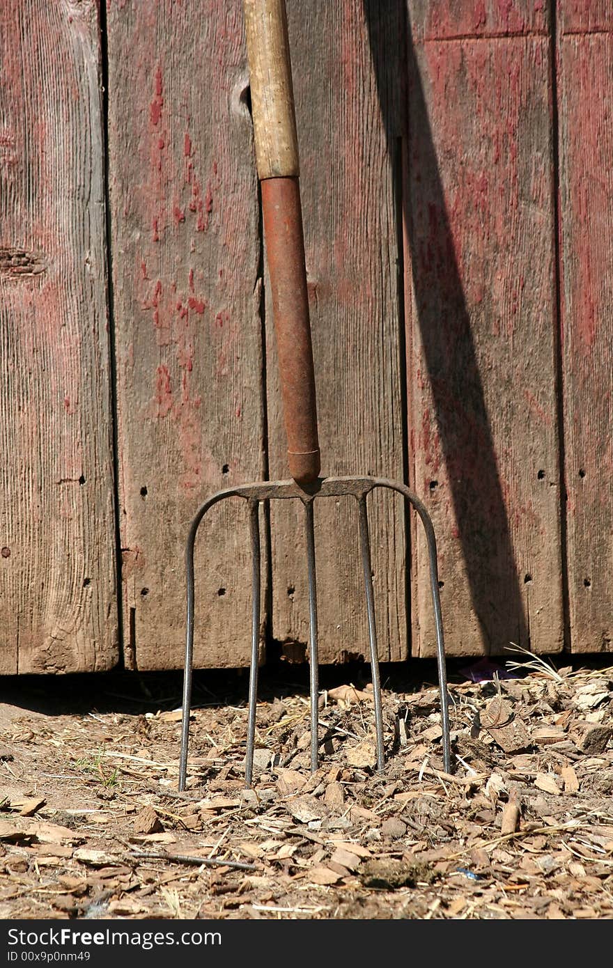 A Pitchfork leaning on a old red barn