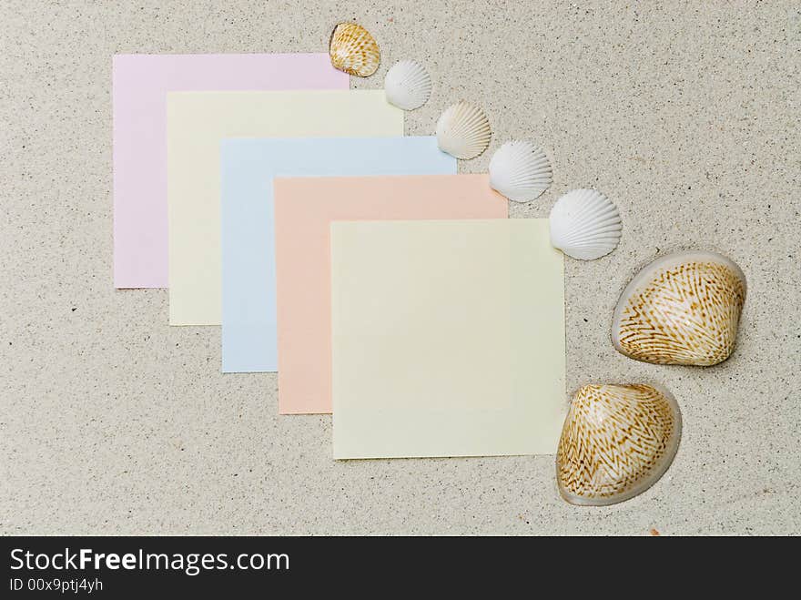 Colored notes with seashells on coral sand