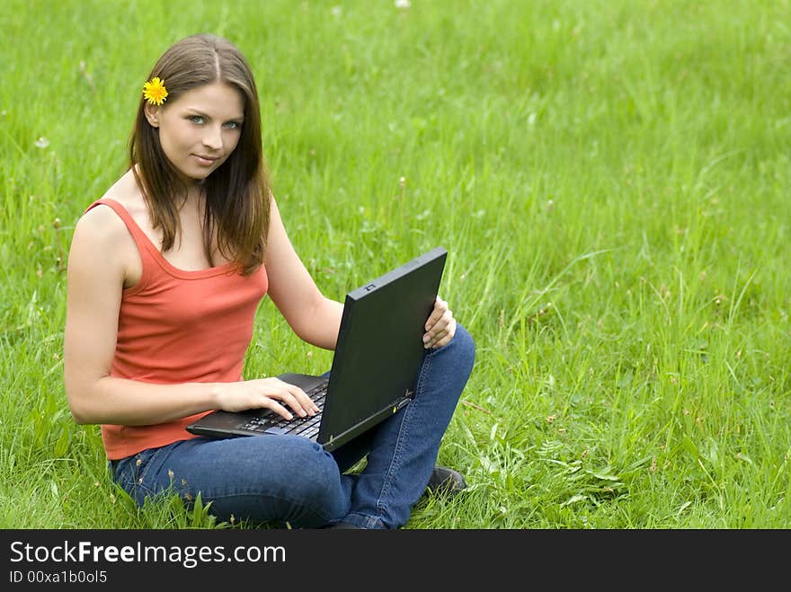 Young business woman relaxing, working on laptop computer on meadow.