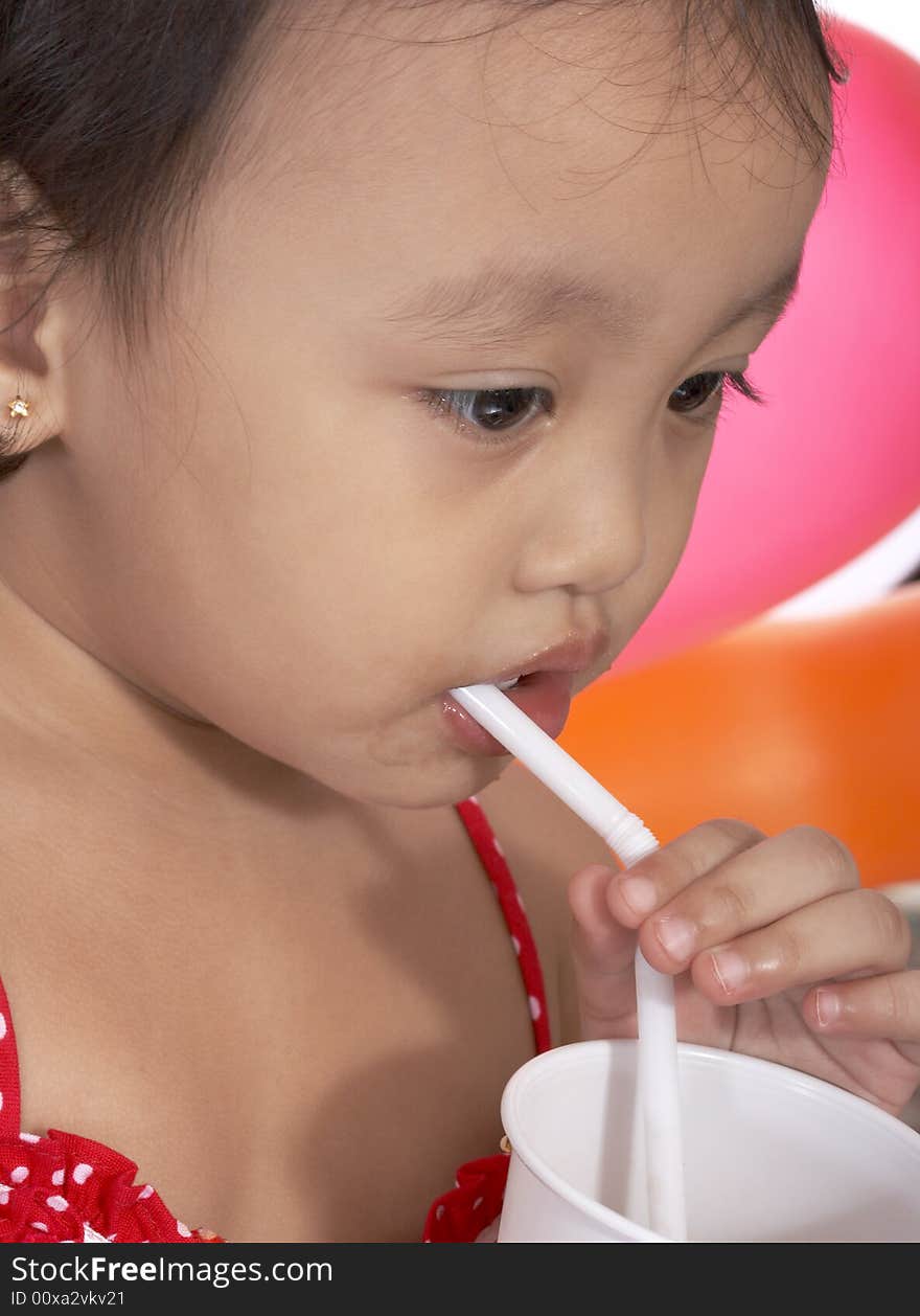 Child sipping juice on a white plastic cup