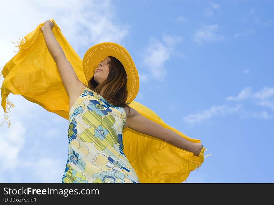 Young woman holding orange wrap against blue sky