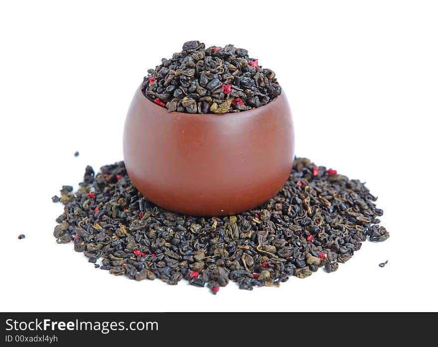 Cup of dried green tea leaves with red flower petal