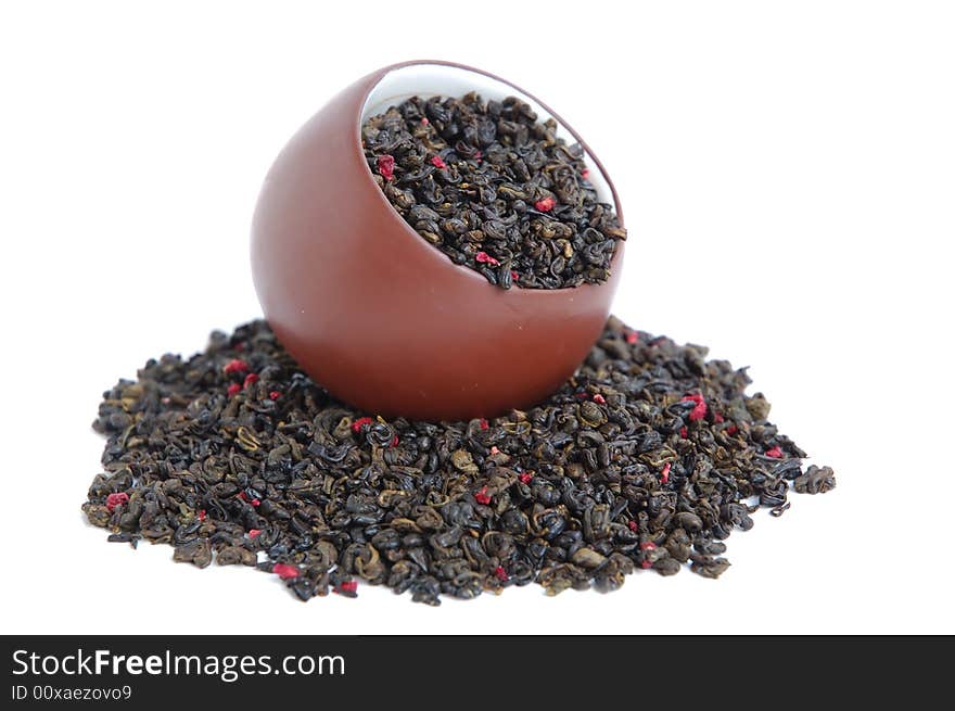 Cup of dried green tea leaves with red flower petal