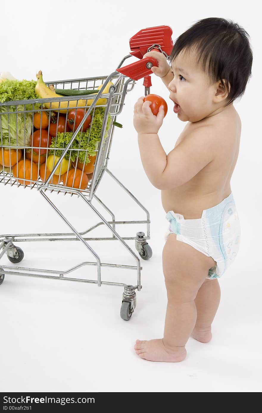 Baby pushes a shopping cart with fruit and vegetables