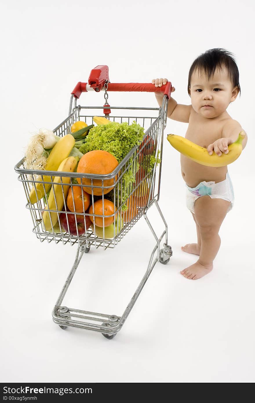 Baby pushes a shopping cart with fruit and vegetables