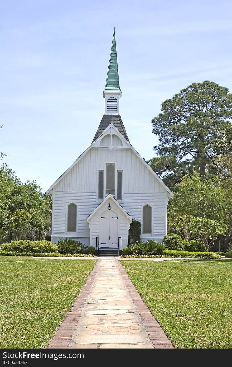 A brick path through a green lawn to a small white church. A brick path through a green lawn to a small white church