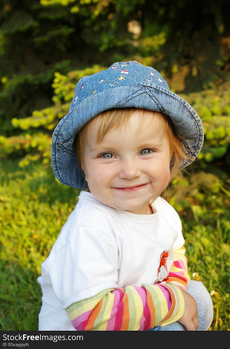 The small beautiful girl sits on a grass and smiles. The small beautiful girl sits on a grass and smiles