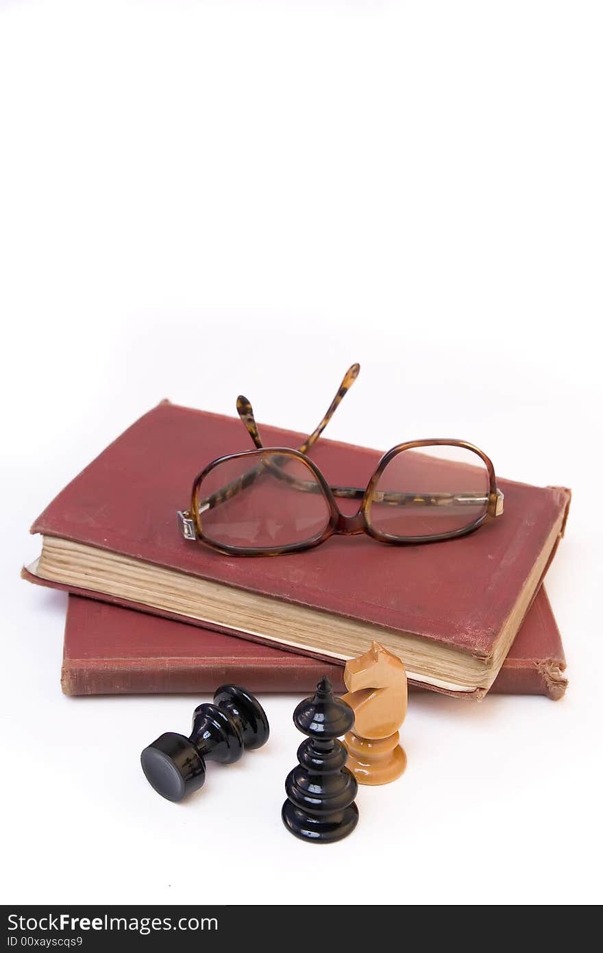 Chess pieces with old book and eyeglasses isolated