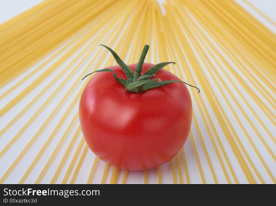 Some spaghetti and a red tomato on a white background. Some spaghetti and a red tomato on a white background