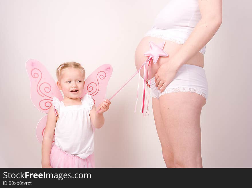 A little fairy points her magic wand at her mothers pregnant belly so that a brother or sister will come out!. A little fairy points her magic wand at her mothers pregnant belly so that a brother or sister will come out!