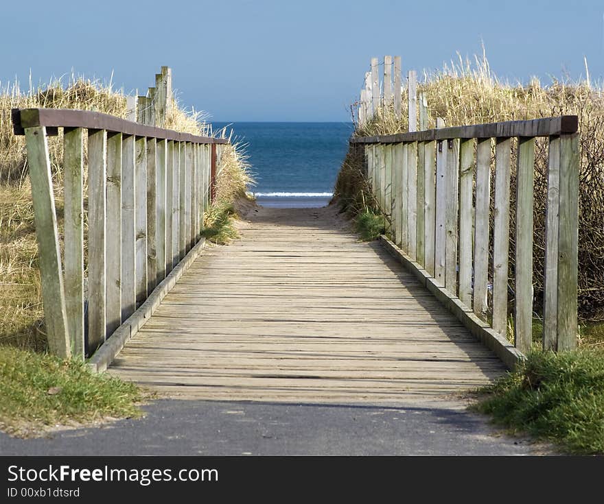 Wooden boardwalk leading to blue sea and beach. Wooden boardwalk leading to blue sea and beach.