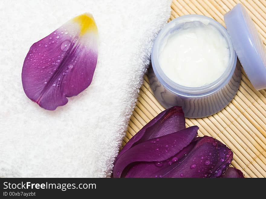 Spa essentials (cream, white towel and violet flower)