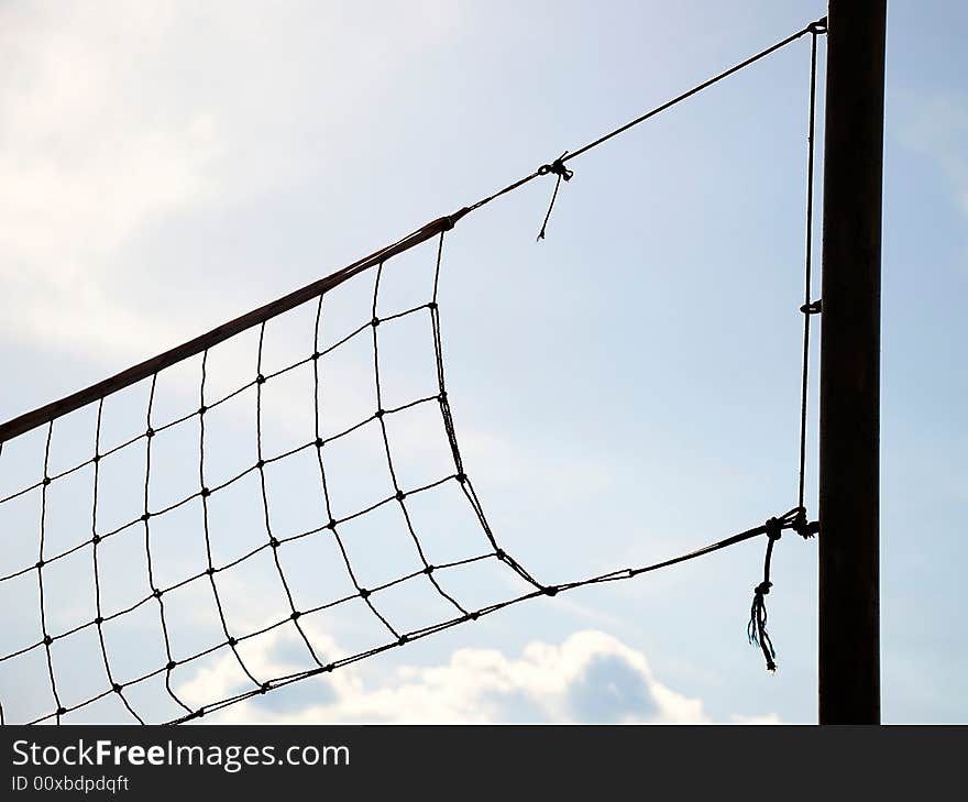 Volleyball net with blue sky and clouds in the background