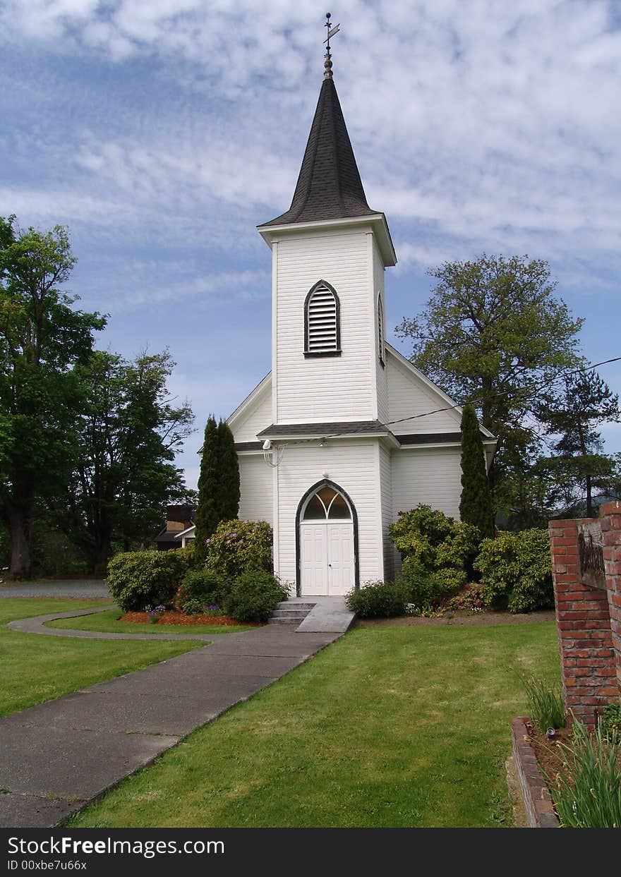 Front view of a country church with blue sky and light fluffy clouds. Front view of a country church with blue sky and light fluffy clouds.