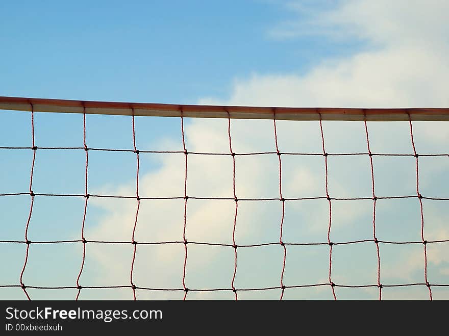 Volleyball net with blue sky and clouds in the background