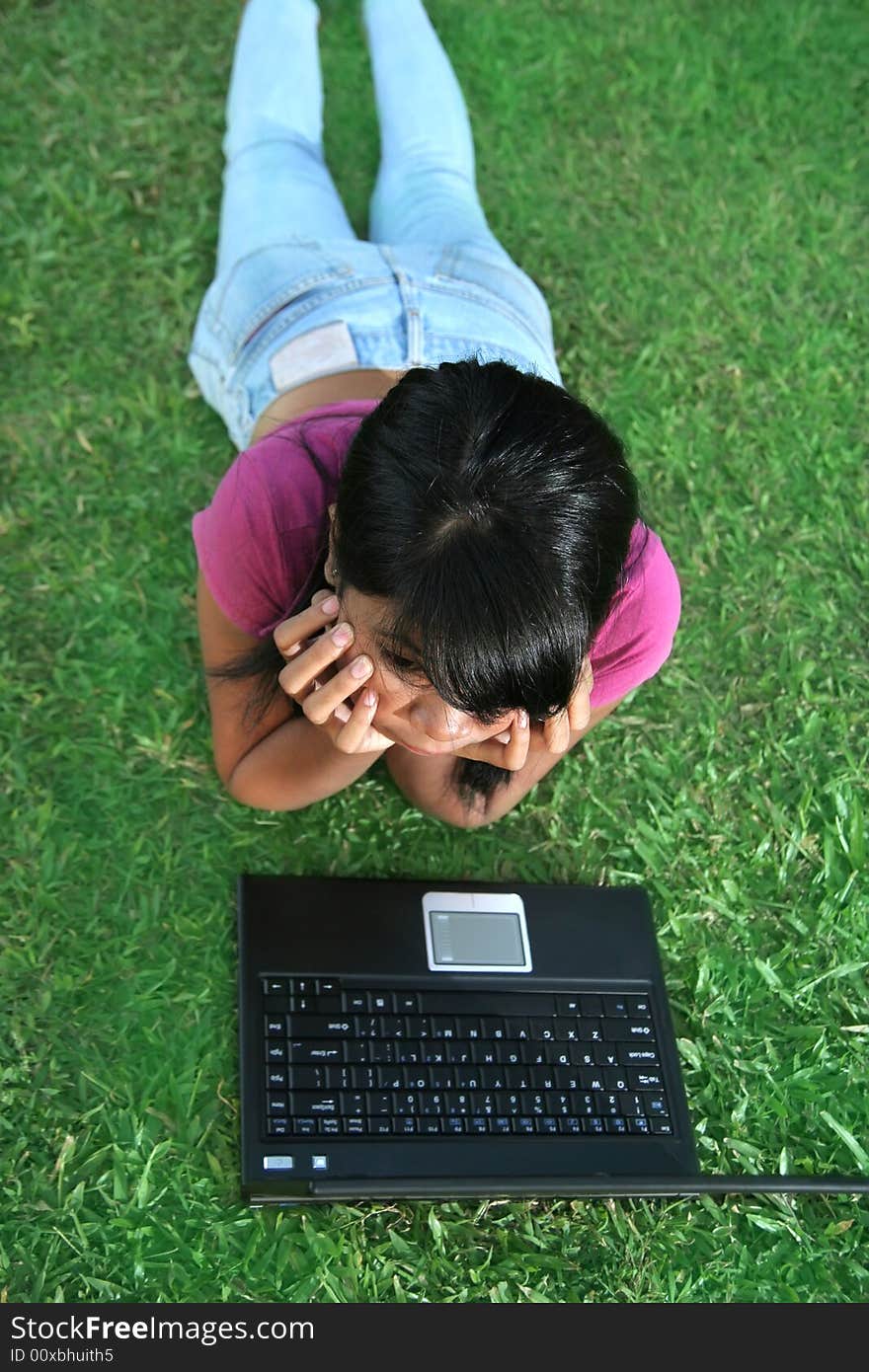 Girl and laptop on the green grass