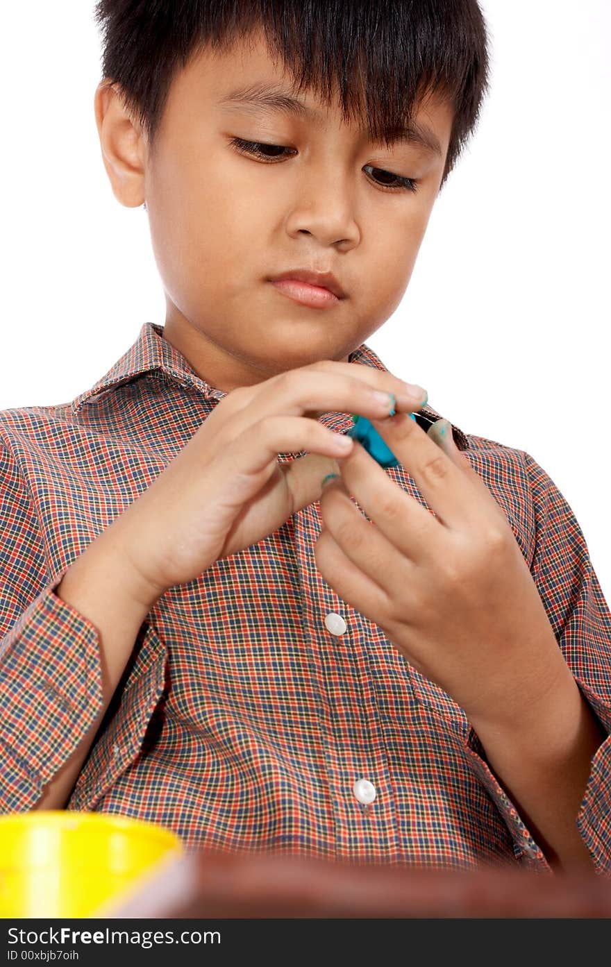 Unsmiling school boy trying to form a figure out of clay