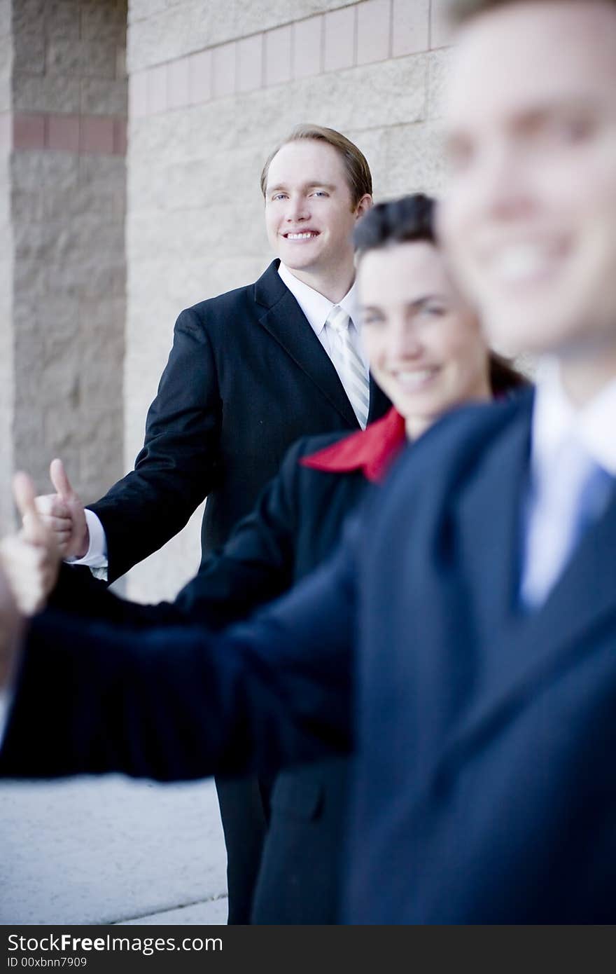 Three business people wearing suits standing in a row all giving thumbs-up. Three business people wearing suits standing in a row all giving thumbs-up