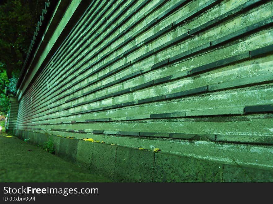 Old style boundary wall around Japanese Temple in Tokyo, Japan;
focus on front part with yellow leafs