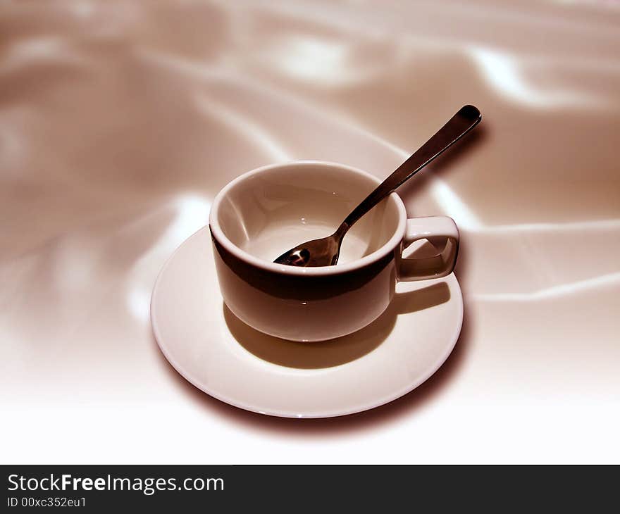 A cup and tea spoon with textile background