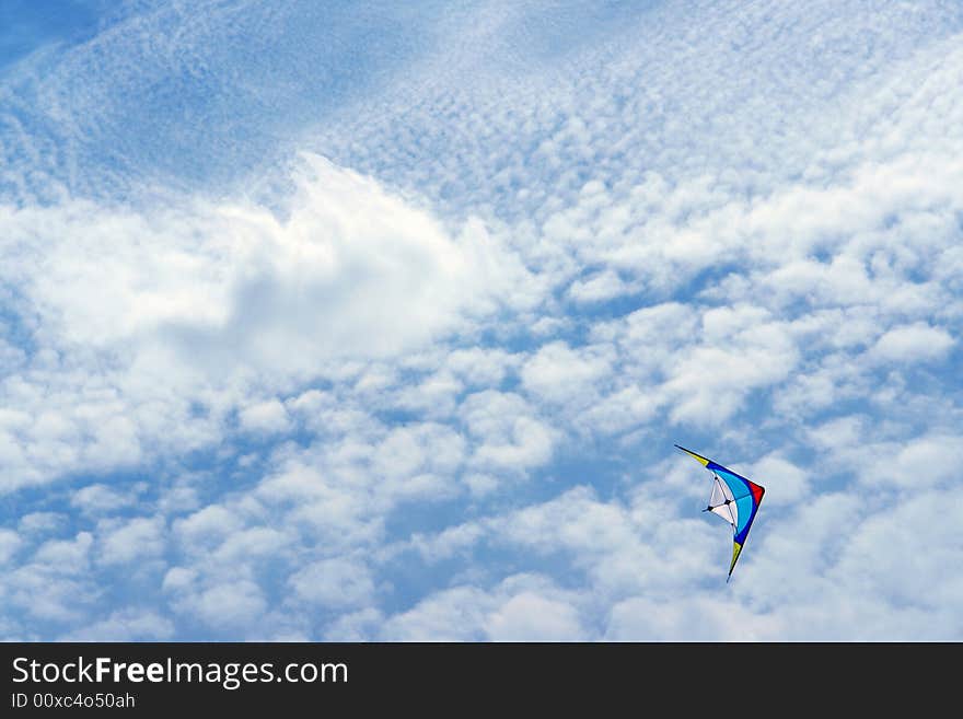 Colored kite agaisnt in a blue sky with clouds. Colored kite agaisnt in a blue sky with clouds