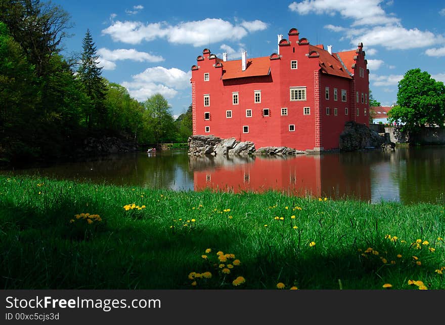 Castle Cervena Lhota built up in manor house style with red colored walls at little island surrounded by water of pond in south part of the Czech Republic