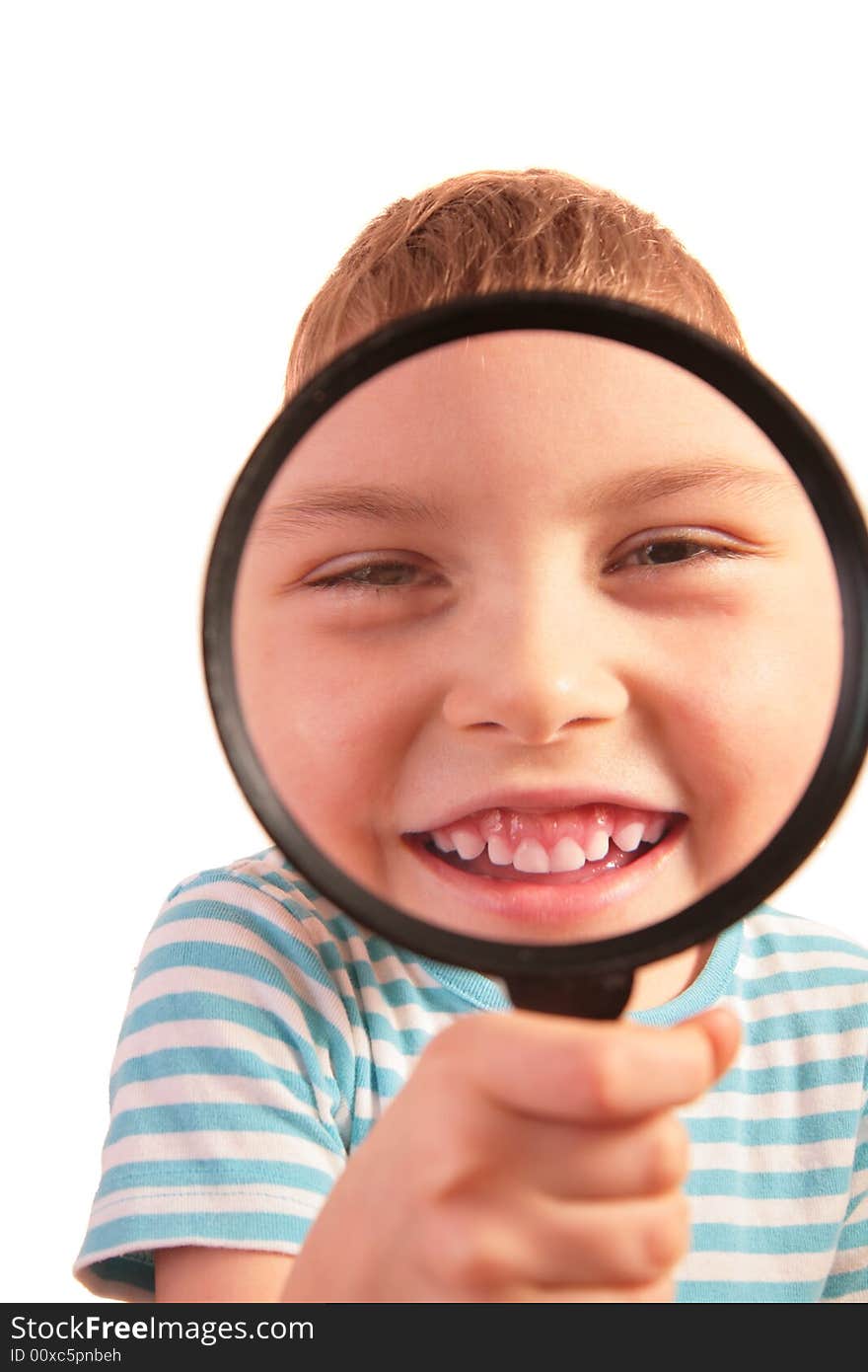 Smiling child looks through magnifier on white