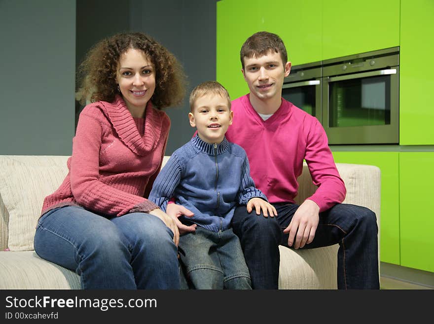 Family of three sits on sofa. Family of three sits on sofa