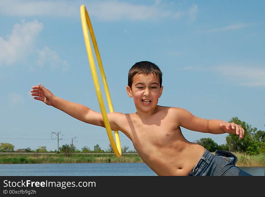 Boy doing his sportive exersices with a hoop on the bank of the river. Boy doing his sportive exersices with a hoop on the bank of the river