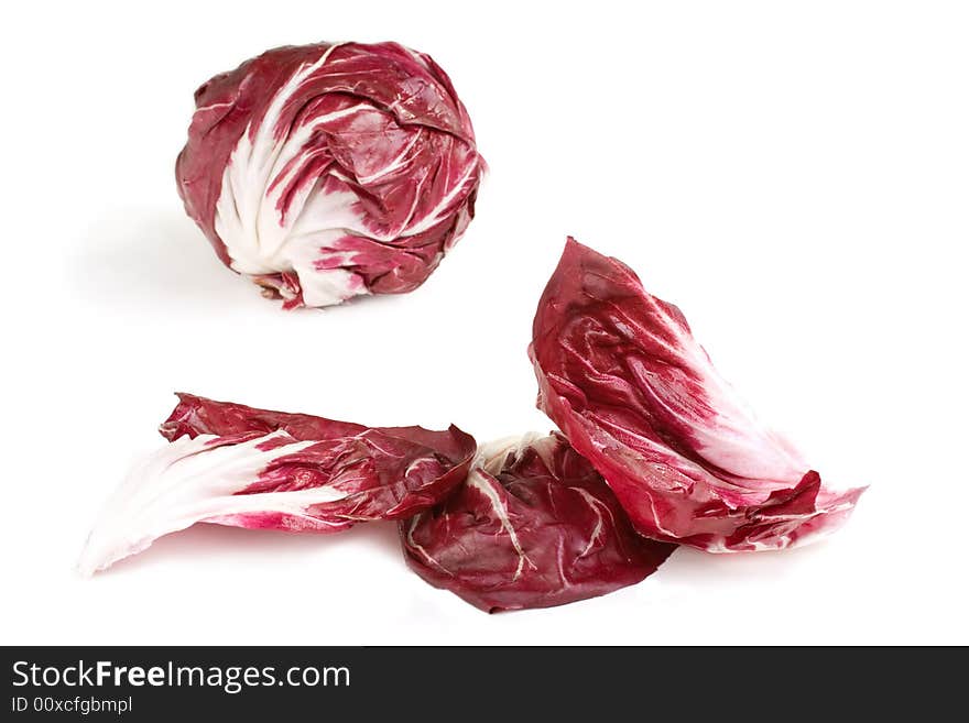 Fresh deep red white veined radicchio leaves with head in background. Fresh deep red white veined radicchio leaves with head in background