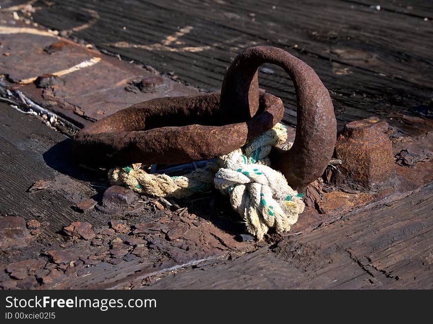 Close up detail of worn iron rings and rope on old dock. Close up detail of worn iron rings and rope on old dock