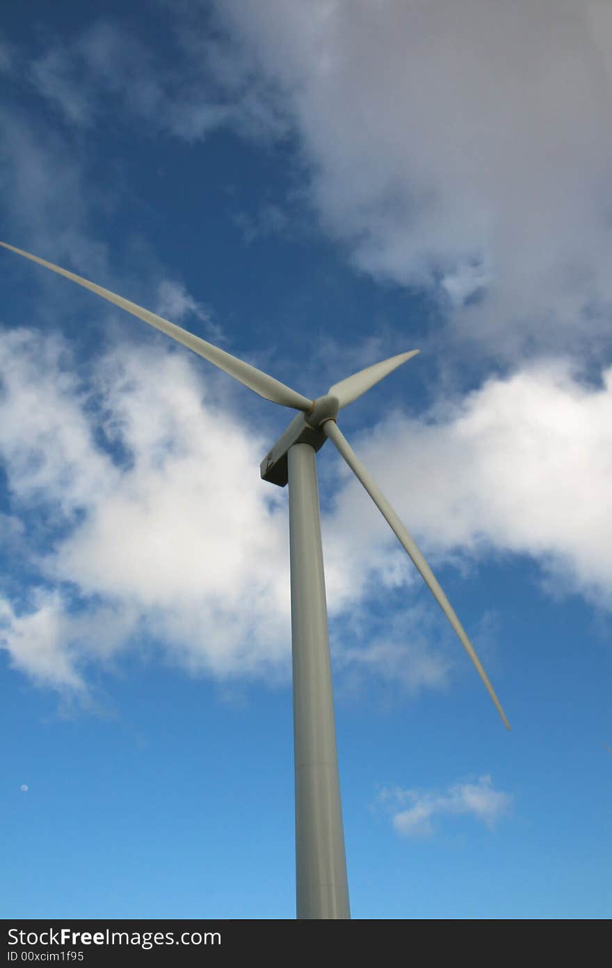 Picture of upper half of a wind turbine against blue cloudy sky