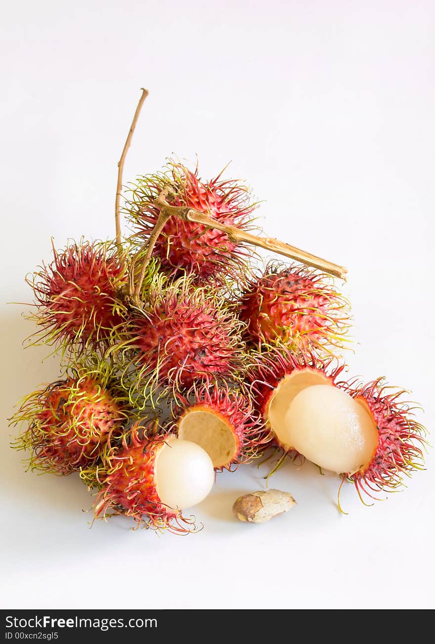 Still life of rambutans still attached to their branches, whole, peeled, and a single seed