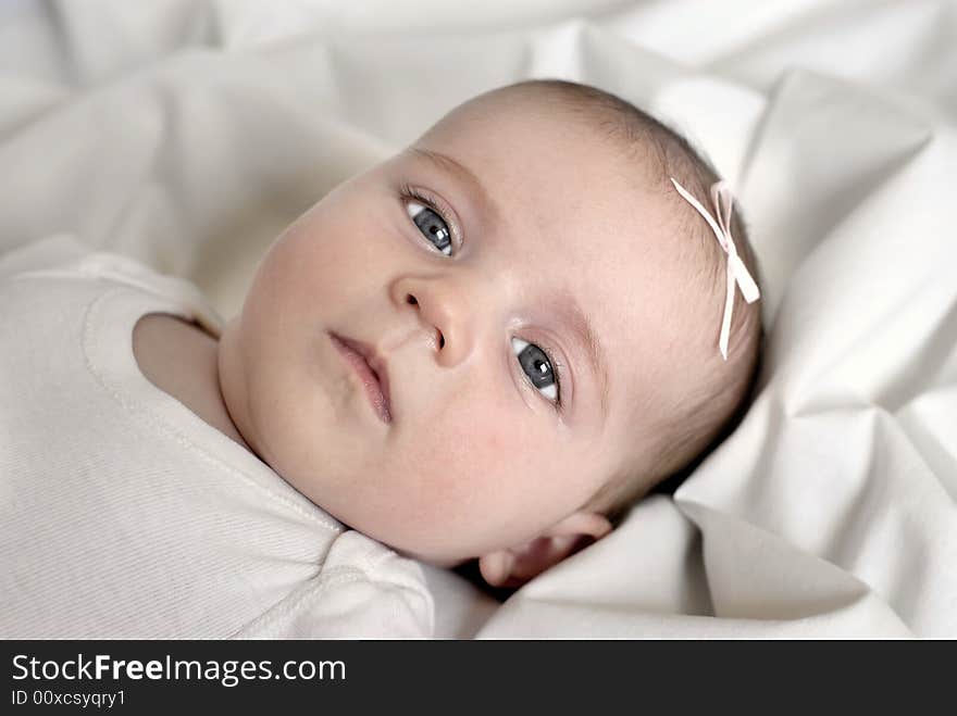 New born baby girl with bow lying on a white blanket. New born baby girl with bow lying on a white blanket