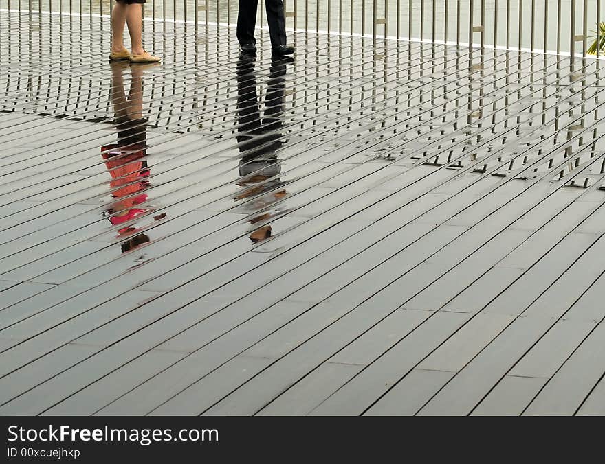 A couple reflected on the wet boardwalk after a tropical afternoon convectional shower. A couple reflected on the wet boardwalk after a tropical afternoon convectional shower