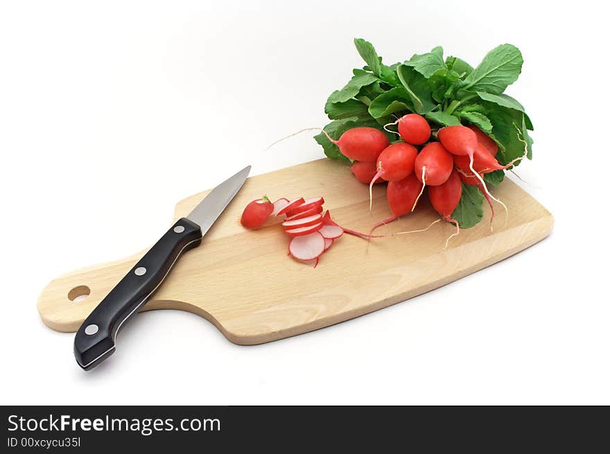 Fresh radishes with knife on chopping board.