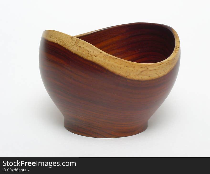 An empty bowl made of Costa Rican rosewood, standing on a plain white backdrop. The bowl is a mid reddish-brown, with light tan edging. An empty bowl made of Costa Rican rosewood, standing on a plain white backdrop. The bowl is a mid reddish-brown, with light tan edging.