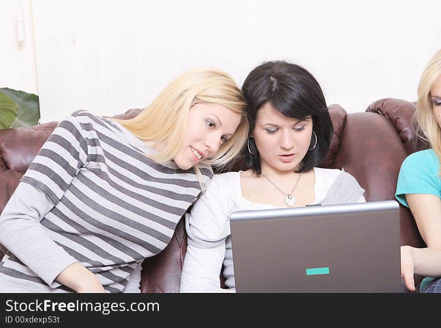 Three girls with laptop surfing on the Internet and having fun. Three girls with laptop surfing on the Internet and having fun