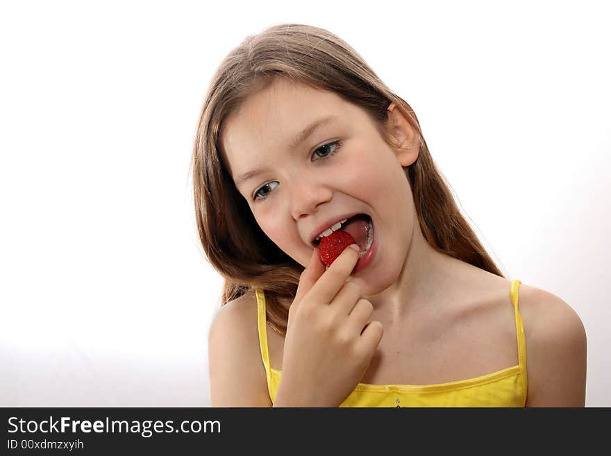 Young, white girl in yellow shirt eats fresh strawberry. White background. Young, white girl in yellow shirt eats fresh strawberry. White background