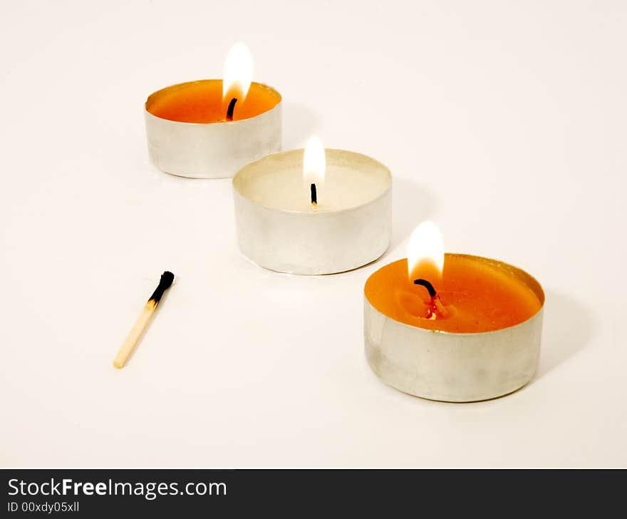 Three candles in a raw lit with a burnt match being near. Three candles in a raw lit with a burnt match being near