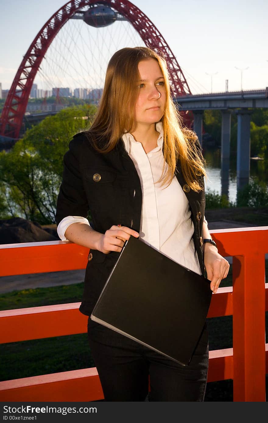 The young businesswoman with a folder on a background of the blue sky