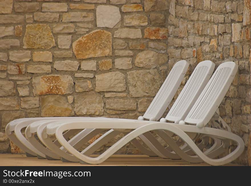 White plastic seats standing on a terrace next to a pool